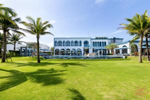 un grand bâtiment avec des palmiers devant dans l'établissement Luxstay apartment Swimming pools and private beach, à Dien Ban