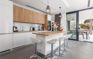 a kitchen with white cabinets and a counter with stools at 4 Bedroom Gorgeous Home In Lun in Lun