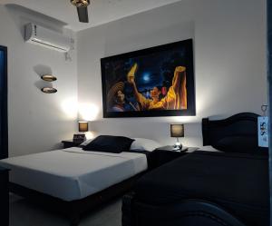 zwei Betten in einem Zimmer mit einem Gemälde an der Wand in der Unterkunft SAES Hotel Boutique in El Banco