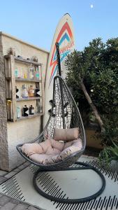 a wicker chair sitting on a patio with a surfboard at Koru House Torvaianica in Torvaianica