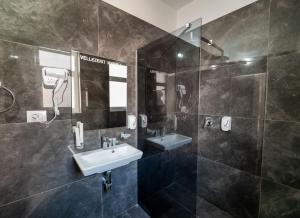 a bathroom with a sink and a shower and a mirror at Hotel Myrtai - City Center in Sarandë