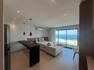 a bedroom with a bed and a desk with a view of the ocean at Lindo Flat na praia de Itaipuacu in Maricá