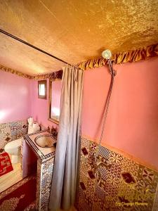 a bathroom with a shower curtain and a sink at Aladdin Desert Camp - Mhamid Erg Chigaga Escape in El Gouera