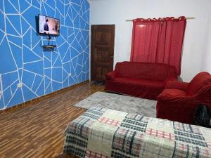 a living room with a couch and a tv on a wall at Casa de aluguel da vitoria in Ubatuba