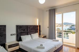 a bedroom with a bed and a large window at Hotel Myrtai - City Center in Sarandë