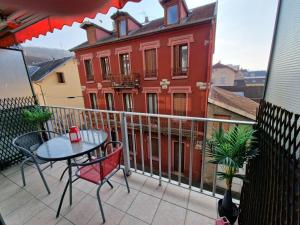 un balcón con mesa y sillas y un edificio rojo en L'Aixotique, en Aix-les-Bains
