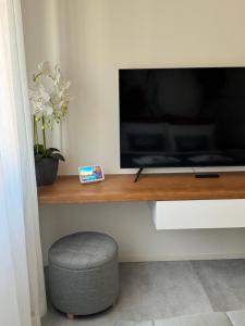 a television on a wooden shelf with a stool at B&B Prestige Apartment - Metropolitana MM1 - Duomo San Babila Milano centro - Castello Sforzesco - Stadio San Siro - Forum Assago - Fiera Milano in Corsico