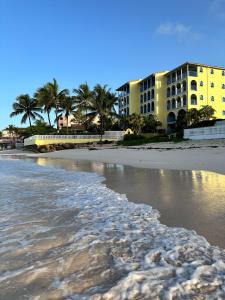 a beach with a yellow building and palm trees at South Coast - Private in Christ Church