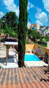een boom naast een zwembad bij Recanto das Pedras hospedagem- Loft Container in São Thomé das Letras