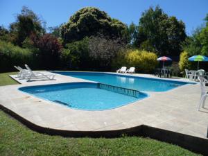 Cabañas Los Tilos Pucón في بوكون: مسبح في ساحة فيها كراسي ومظلة