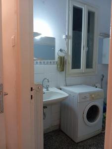 Un baño con lavadora y lavabo. en White Bunk Bed in dorm 5' from metro, en Atenas