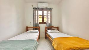 two beds in a room with a window at Casa linda e aconchegante in Gravatá +25 photos