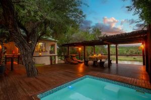 a deck with a pool and a table and a tree at Parsons River Camp in Balule Game Reserve