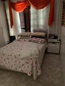 una camera da letto con un letto e un piumone a fiori di Casa família com piscina a Garopaba