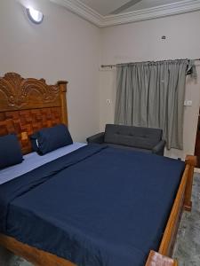a bedroom with a large blue bed and two chairs at George's Enterprise and Residences in Brufut