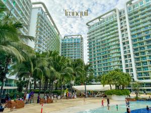 un complejo con palmeras y gente en una piscina en Tranquil Staycation at Azure, en Manila