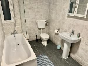 a bathroom with a tub and a toilet and a sink at Central London Private Bedrooms in Finsbury Park Station in London