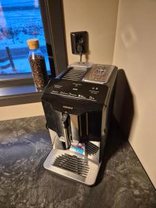 a black espresso machine sitting on a counter next to a window at Villa Walter Lofoten with SAUNA in Kvalnes