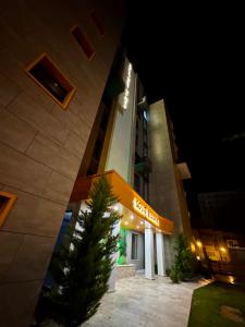 un edificio con un árbol delante de él por la noche en Solid Residence Melody, en Mamaia