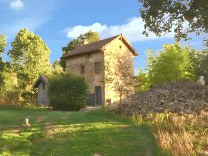 a stone house with a stone wall in the yard at Maison charmante à Charron avec piscine partagée in Charron