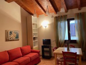 un soggiorno con un divano rosso e un tavolo di Albergo Commercio - Ristorante Mas-cì a Clusone