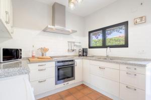a white kitchen with white cabinets and a window at Villa Tosalet Pomelo in Jávea