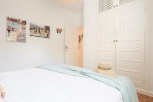 a white bedroom with a bed with a hat on it at Villa Tosalet Pomelo in Jávea
