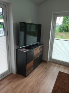 a tv sitting on a dresser in a room with two windows at Chalet Ostfriesenruhe in Großefehn 