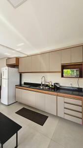a kitchen with white cabinets and a white refrigerator at White House - Taipú de Fora in Barra Grande