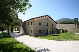 an old stone building with a road next to it at Le Calvie, country house in Camerino