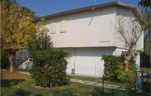 a white building with a tree in front of it at Lovely Apartment In Rosolina Mare in Rosolina Mare