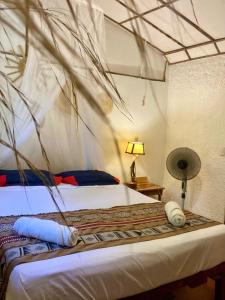 a bedroom with a bed with a mosquito net at Caracolito Hostal in Las Peñitas