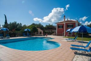 a swimming pool with chairs and umbrellas and a house at Leventis Villas Complex with Sharing Pool in Spartià