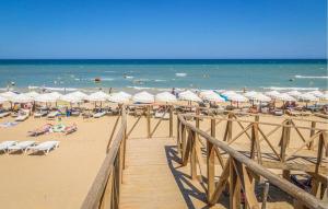 ein Strand mit vielen Sonnenschirmen und Stühlen und dem Meer in der Unterkunft 3 Bedroom Cozy Home In Rojales in Rojales + 24 Fotos