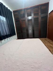 a bedroom with a large bed and wooden closet at Quarto para Hóspedes in Itanhaém