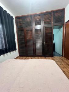 a bedroom with wooden closet doors and a bed at Quarto para Hóspedes in Itanhaém