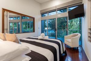 1 Schlafzimmer mit 2 Betten, einem TV und Fenstern in der Unterkunft Diamond by the sea - Direct beach access in Newell Beach + 27 Fotos