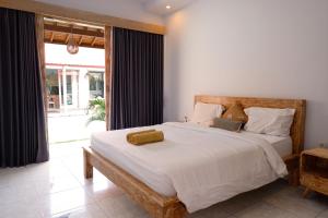 une chambre avec un grand lit et une grande fenêtre dans l'établissement Villa Megadana Munggu, à Canggu