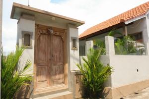 une maison avec une porte en bois sur le côté dans l'établissement Villa Megadana Munggu, à Canggu