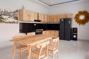 - une cuisine avec une table en bois et un réfrigérateur noir dans l'établissement Villa Megadana Munggu, à Canggu