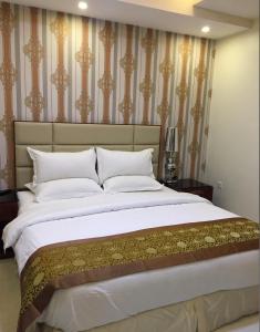 a bedroom with a large bed with gold and white pillows at مسكن لؤلؤة الخليج للشقق المخدومة in Dammam