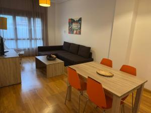 a living room with a couch and a table and chairs at Apartamentos El Caxigu in Arenas de Cabrales