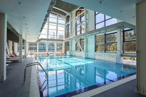 a large swimming pool in a building with windows at Maisonette Mountain View - Euphoria Resort in Borovets