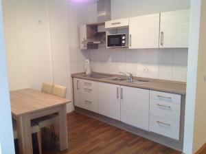 eine Küche mit weißen Schränken, einem Tisch und einem Waschbecken in der Unterkunft Ferienwohnung Fiwa FeWo-1 und FeWo-2 in Pirmasens