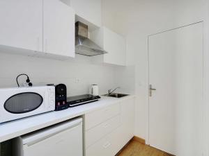 a white kitchen with a microwave on a counter at Spacious Studio - 2P - Levallois-Perret in Levallois-Perret