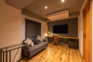 ein Wohnzimmer mit einer Couch und einem Schreibtisch mit einem Fernseher in der Unterkunft Fukuyama Royal Hotel - Vacation STAY 36228v in Fukuyama