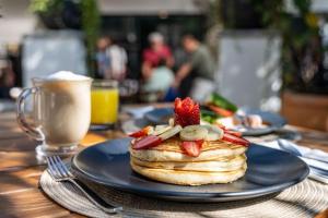 a plate of pancakes with strawberries and fruit on a table at Tatala Hotel & Garden in Tepoztlán