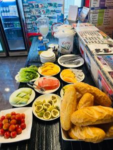 a table with plates of bread and fruits and vegetables at Vangvieng Rock Backpacker Rooftop Hostel in Vang Vieng