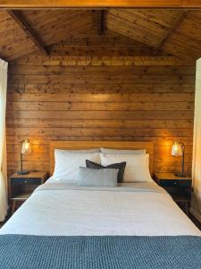 a bedroom with a bed with wooden walls and two lamps at Jacaranda Cottage 5 min by Train or 7 min drive to Parramatta City in Wentworthville