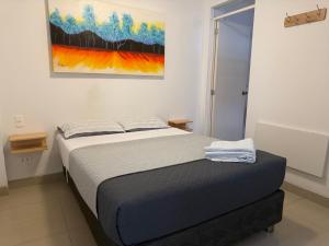 a bed in a bedroom with a painting on the wall at SG Paracas Hostel in Paracas